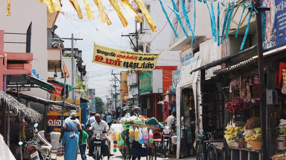 Lane with shops, pedestrians and motorbikes in southern India