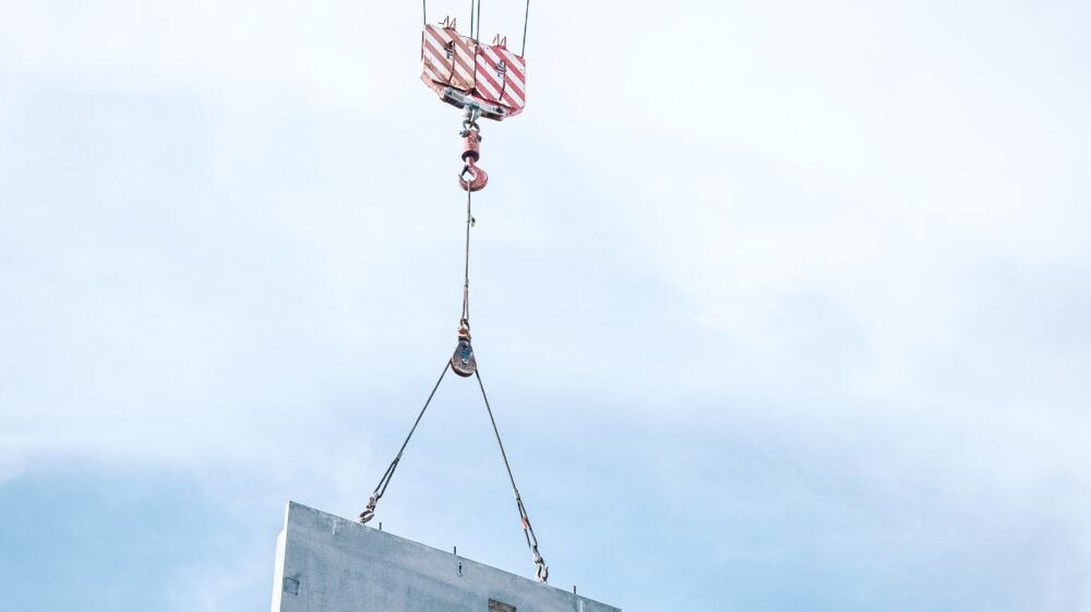 Gray steel frame being lifted by a crane