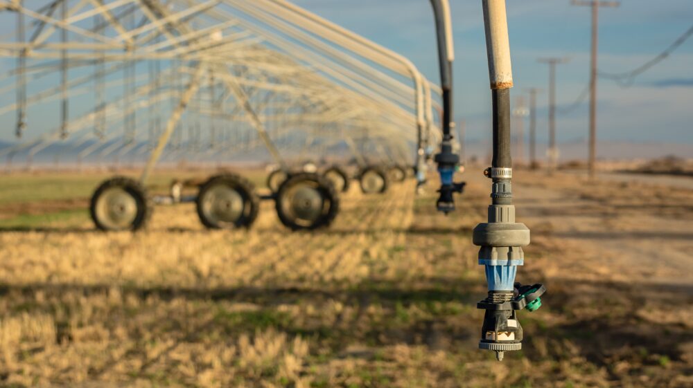 Center-pivot irrigation system hovers over dry agricultural field, Southern California, US