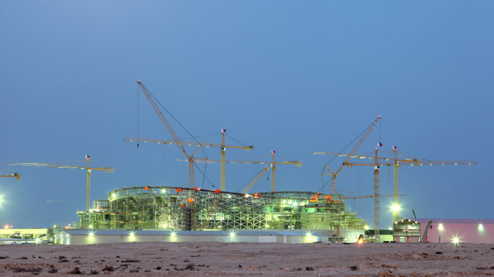 Construction cranes hover over a World Cup stadium-in-progress in Qatar, Middle East