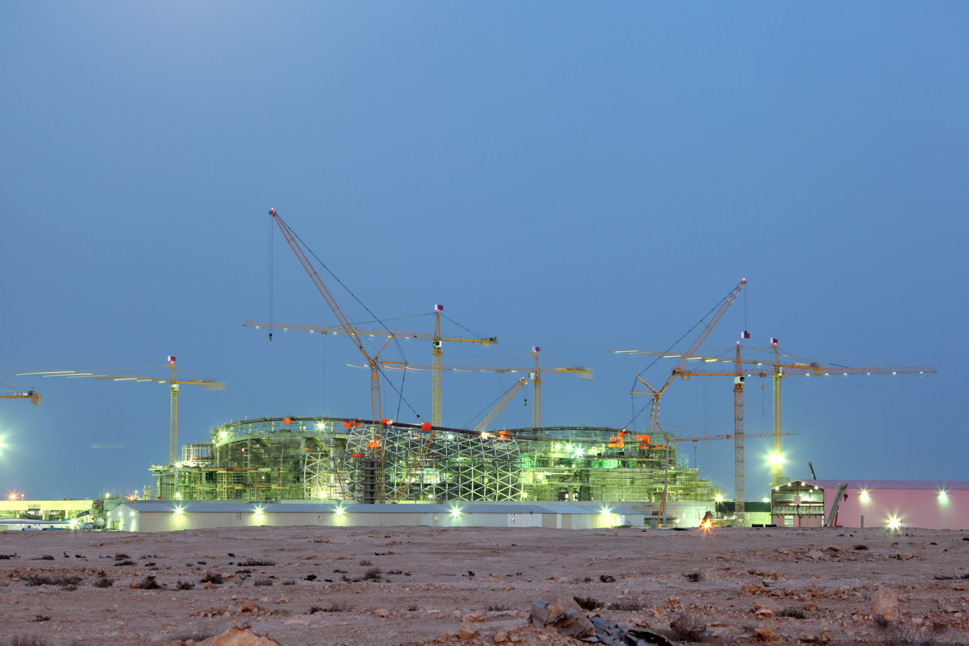 Construction cranes hover over a World Cup stadium-in-progress in Qatar, Middle East