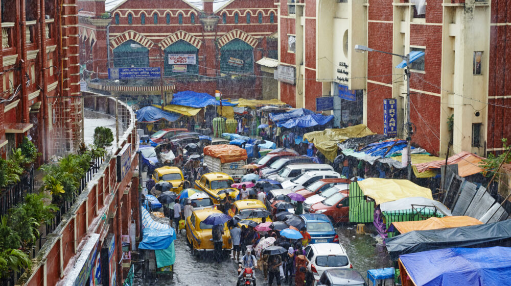 Car, bicycle and foot traffic coalesce amid a monsoon in the New Market area of Kolkata, India.
