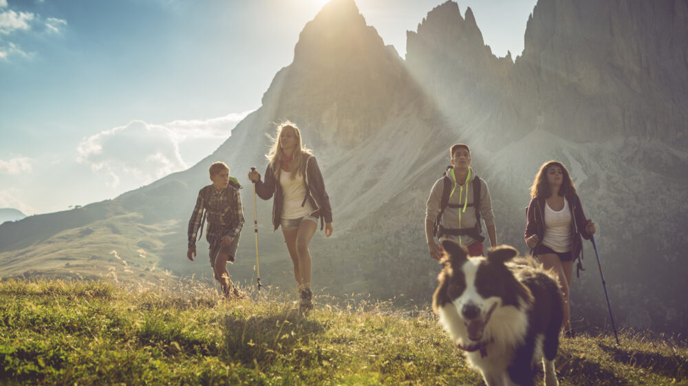 Young people hiking in Dolomites with dog
