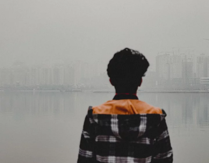 Man overlooking body of water with high rises on other side under construction, Tehran, Iran