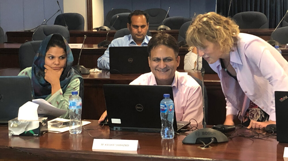 An SEI researcher and trainees in Pakistan look at a laptop computer during a training on SEI's energy modelling software, LEAP