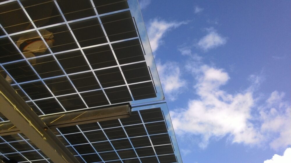 Solar panels under blue sky with white clouds