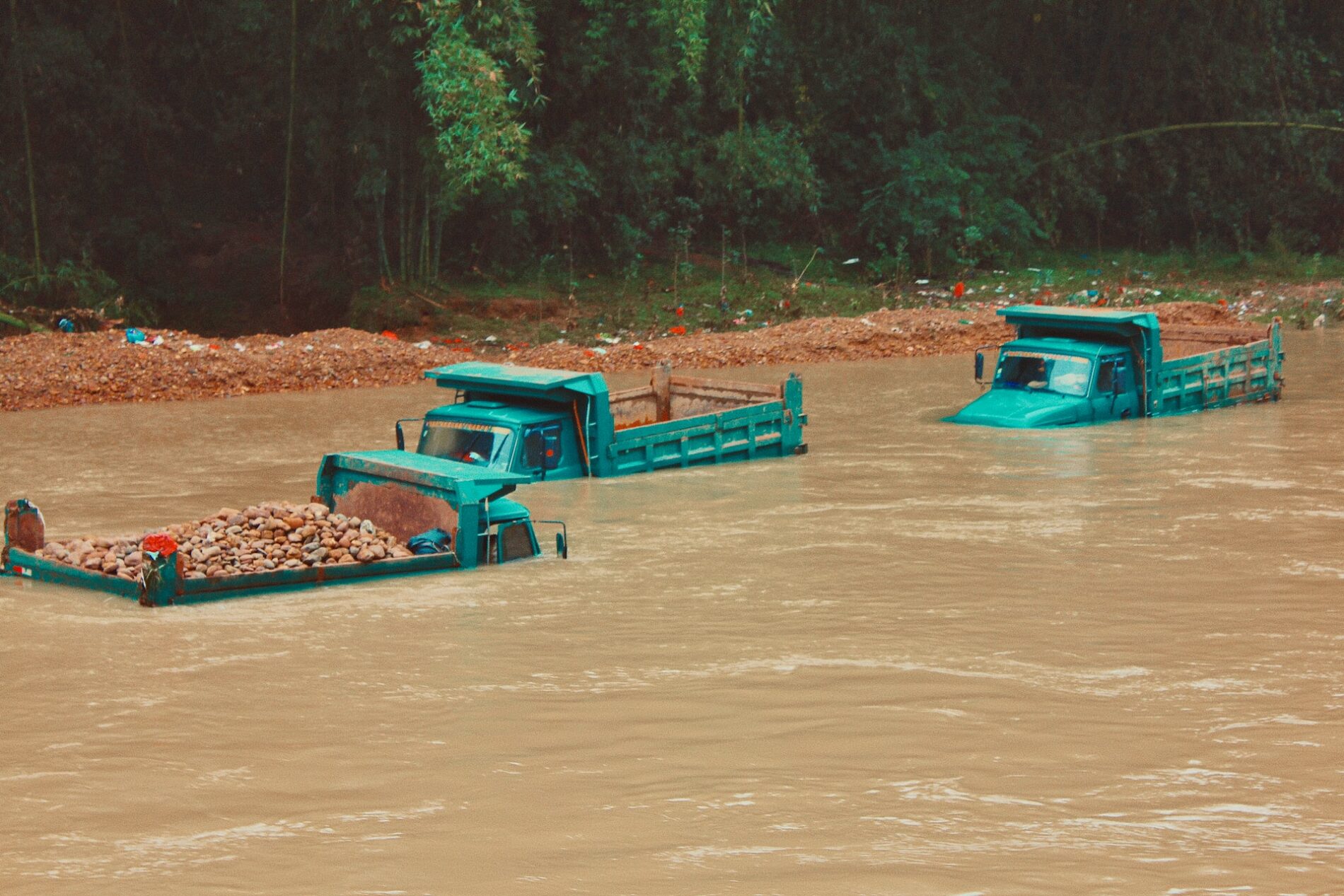 Green trucks submerged in muddy water
