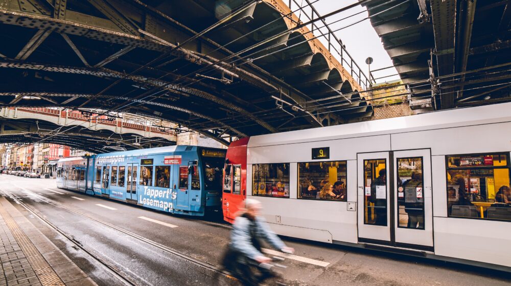 Stadtbahn under bridge in rain passing cyclist, Cologne, Germany