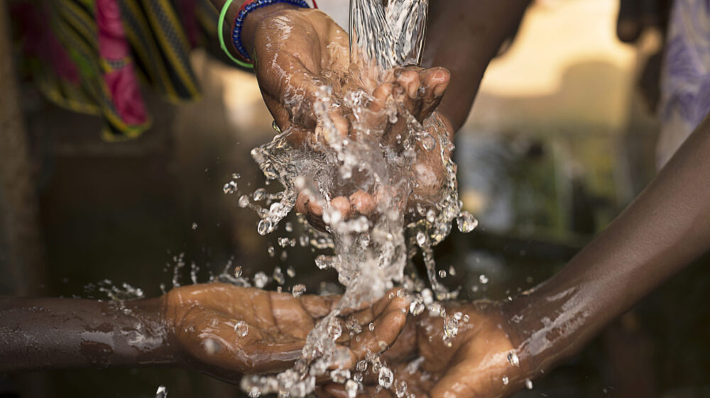 Stream of water pouring into children’s hands.