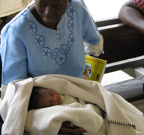 Kenyan woman holding a newborn baby in a blanket