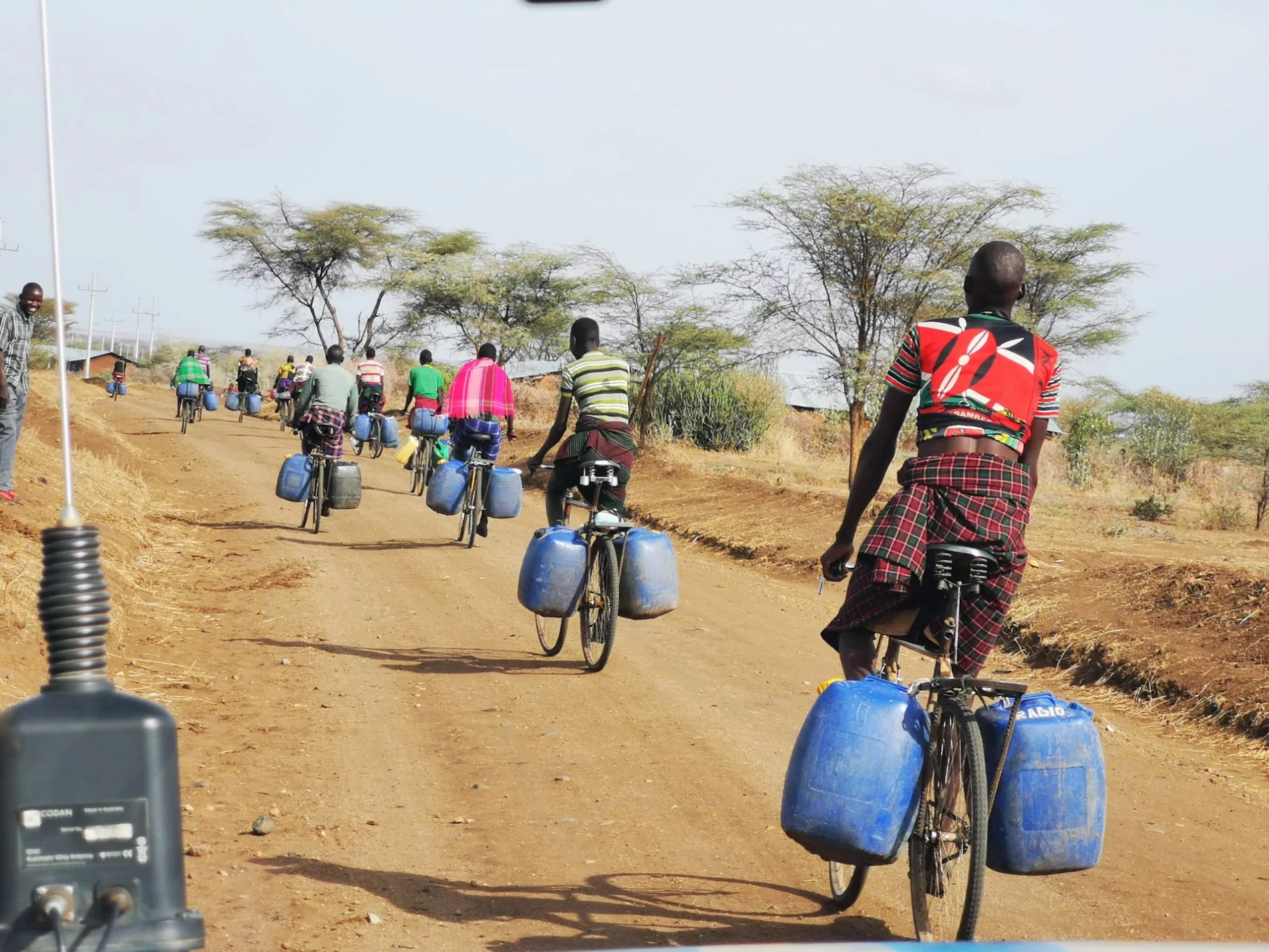 A group of people riding bikes down a road with carrying containers for water