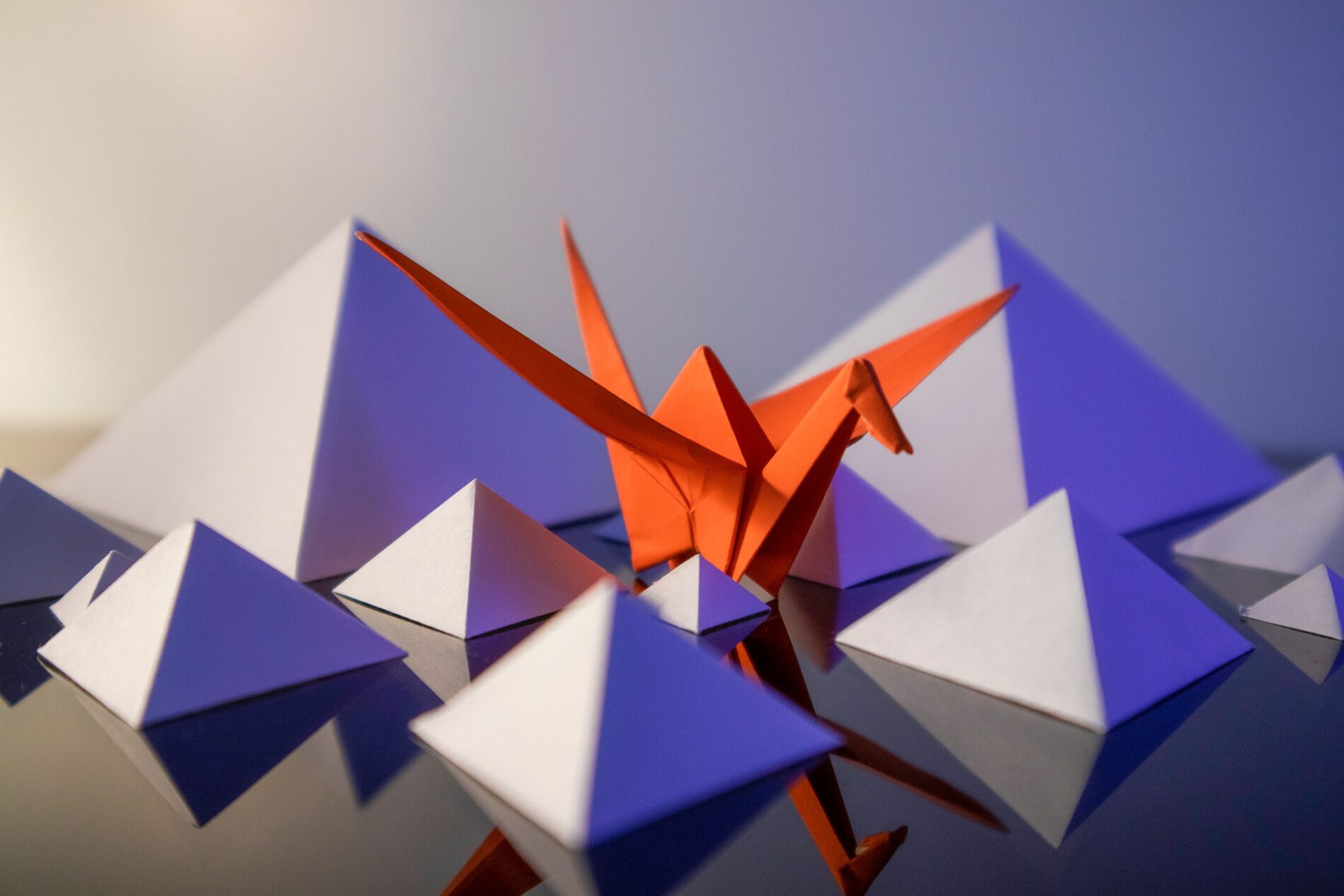 White paper pyramids with orange paper crane