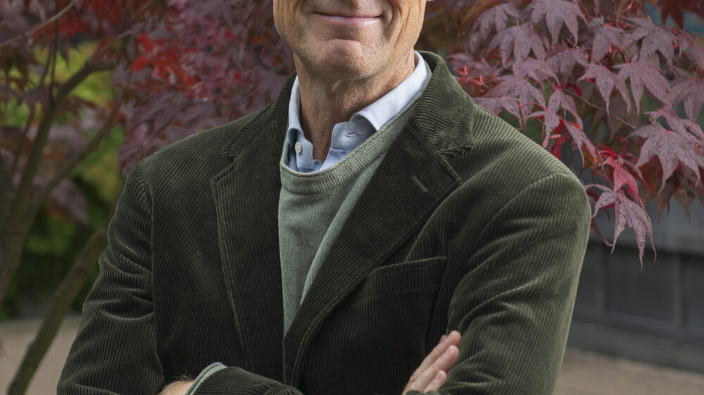 Smiling man with glasses wearing a green suit jacket