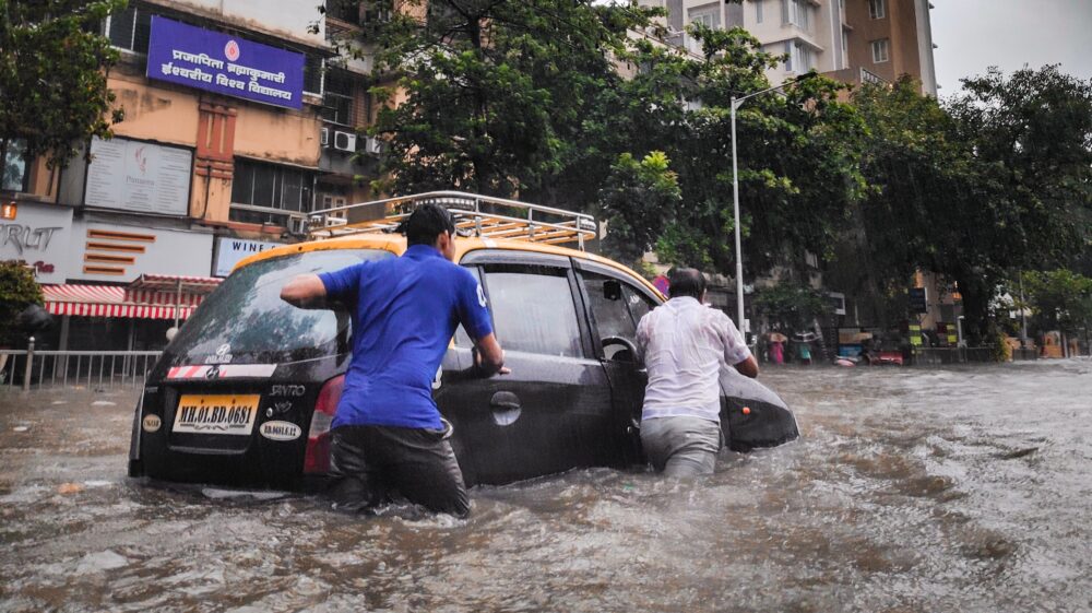 Men pushing car through flooded streets
