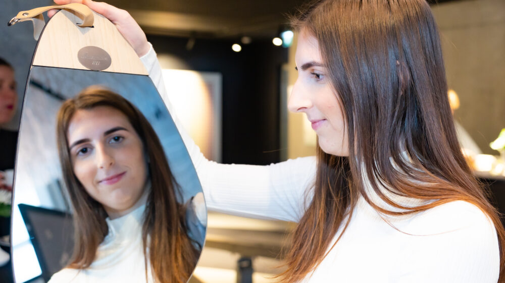 A smiling SEI Tallinn Programme Assistant Kertu Uiboleht in white top holds award, a mirror with her reflection.
