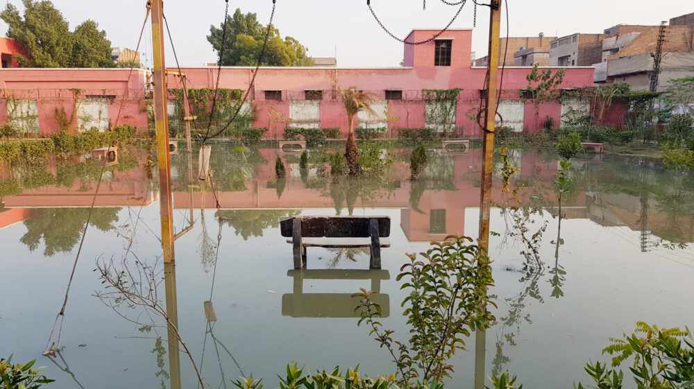 A bench and play equipment are inundated with water amid flooding at a public park in Pakistan.