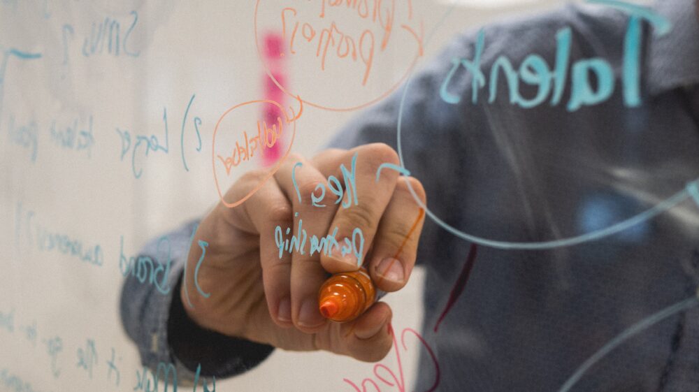 Writing with orange marker on transparent whiteboard