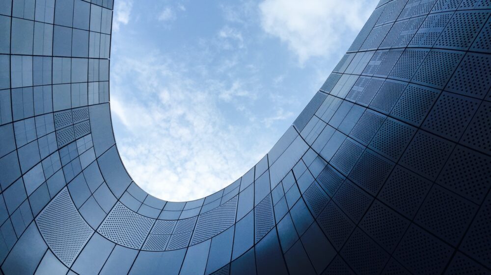 View from below of winding steel building under blue sky with clouds, Dongdaemun, Seoul, South Korea