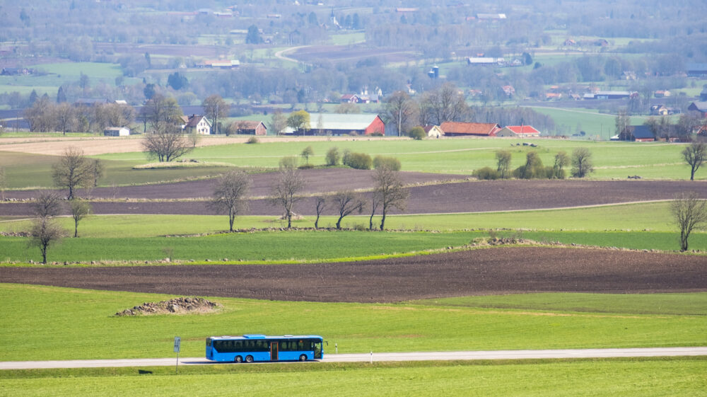 Scenic view of agricultural field with blue bus driving past, Falköping, Sweden