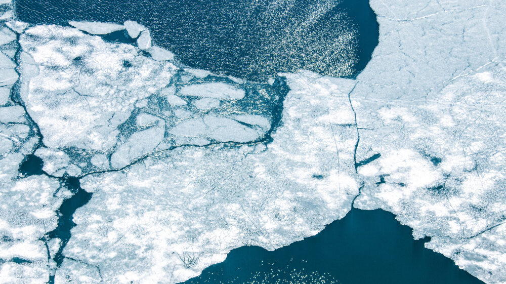 Aerial zenithal view of lake with ice melting.