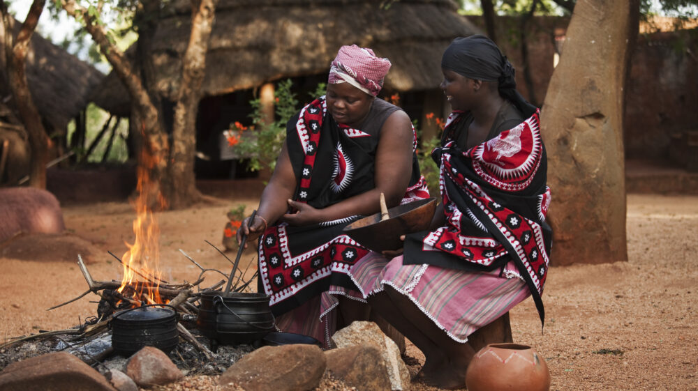 Two women cook around a wood-burning fire in South Africa.