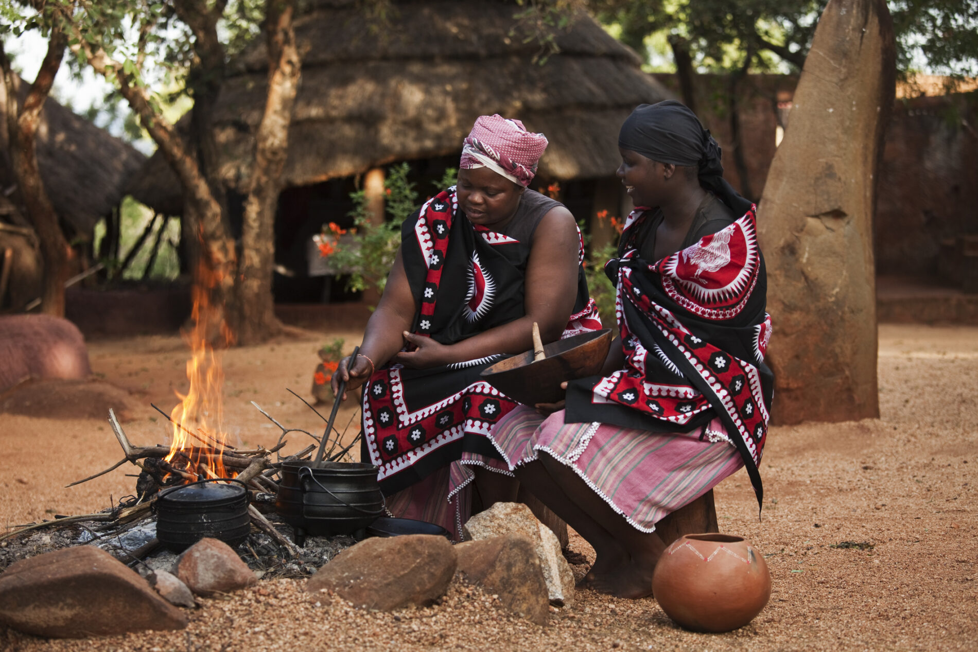 Two women cook around a wood-burning fire in South Africa.