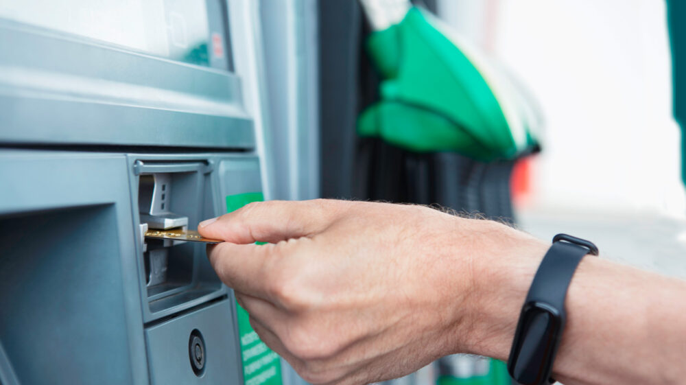 A man's hand inserting a credit card into a gas pump in Sweden.
