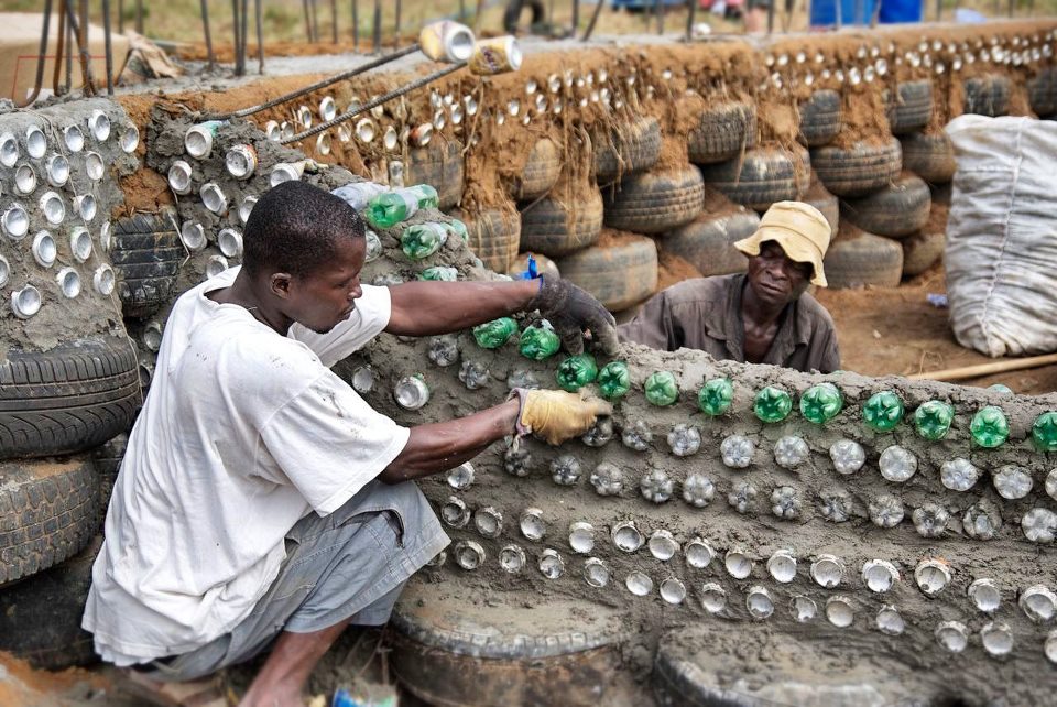 Two men help build a home from recycled materials in Malawi