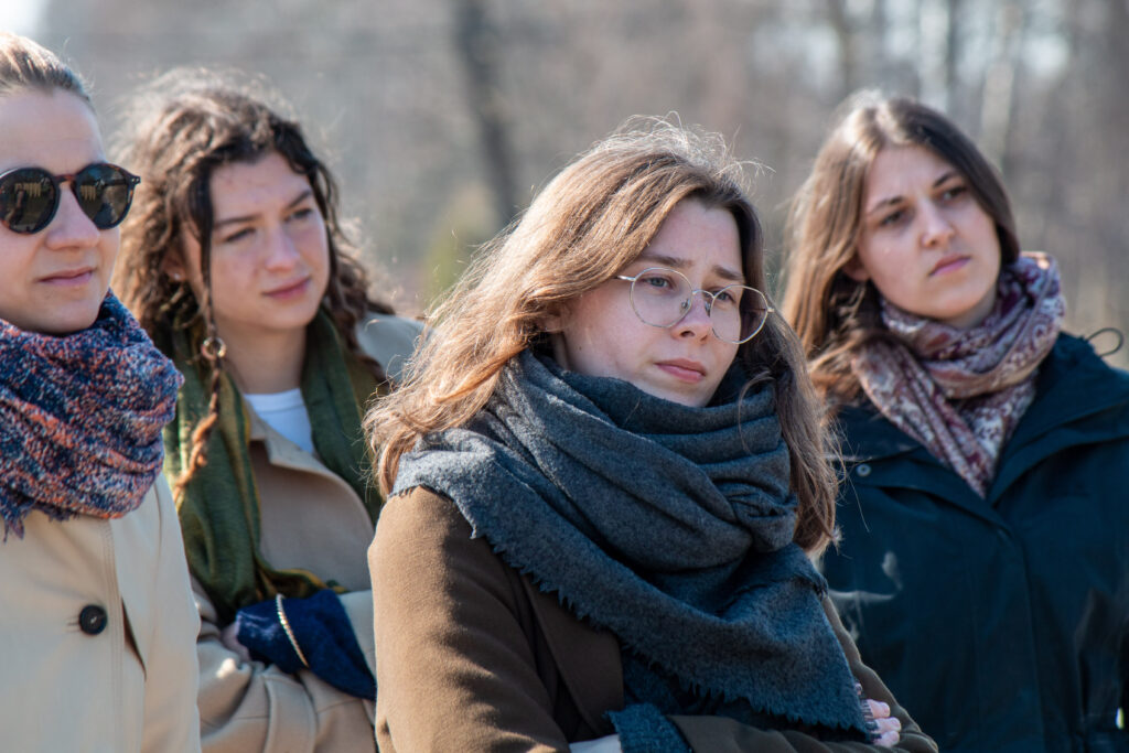 Four young women standing and looking forward, as if listening to someone.