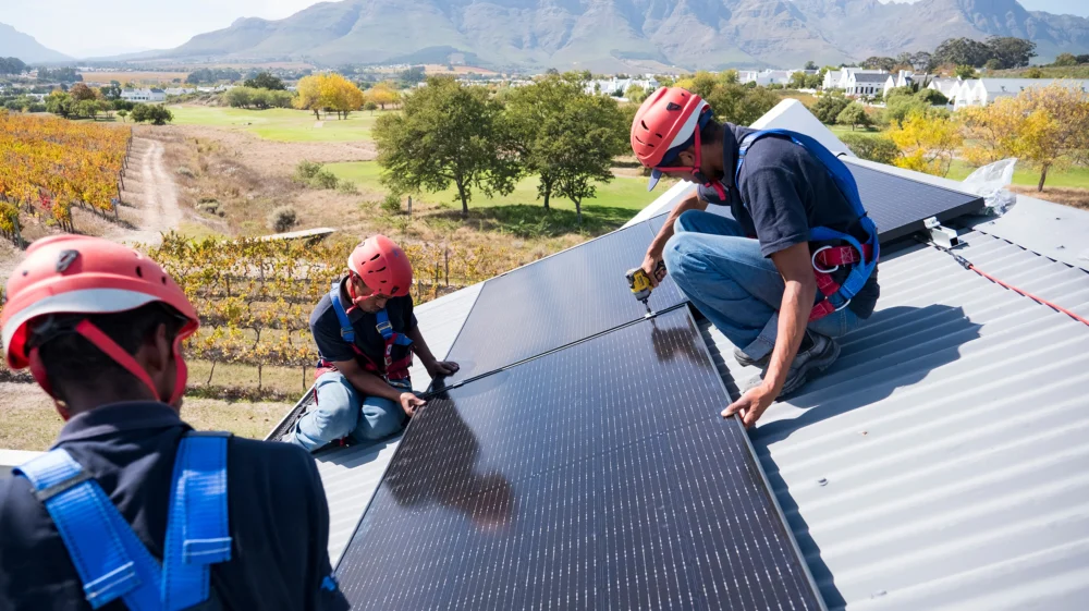 Workers install solar panels on a house in Cape Town, South Africa.