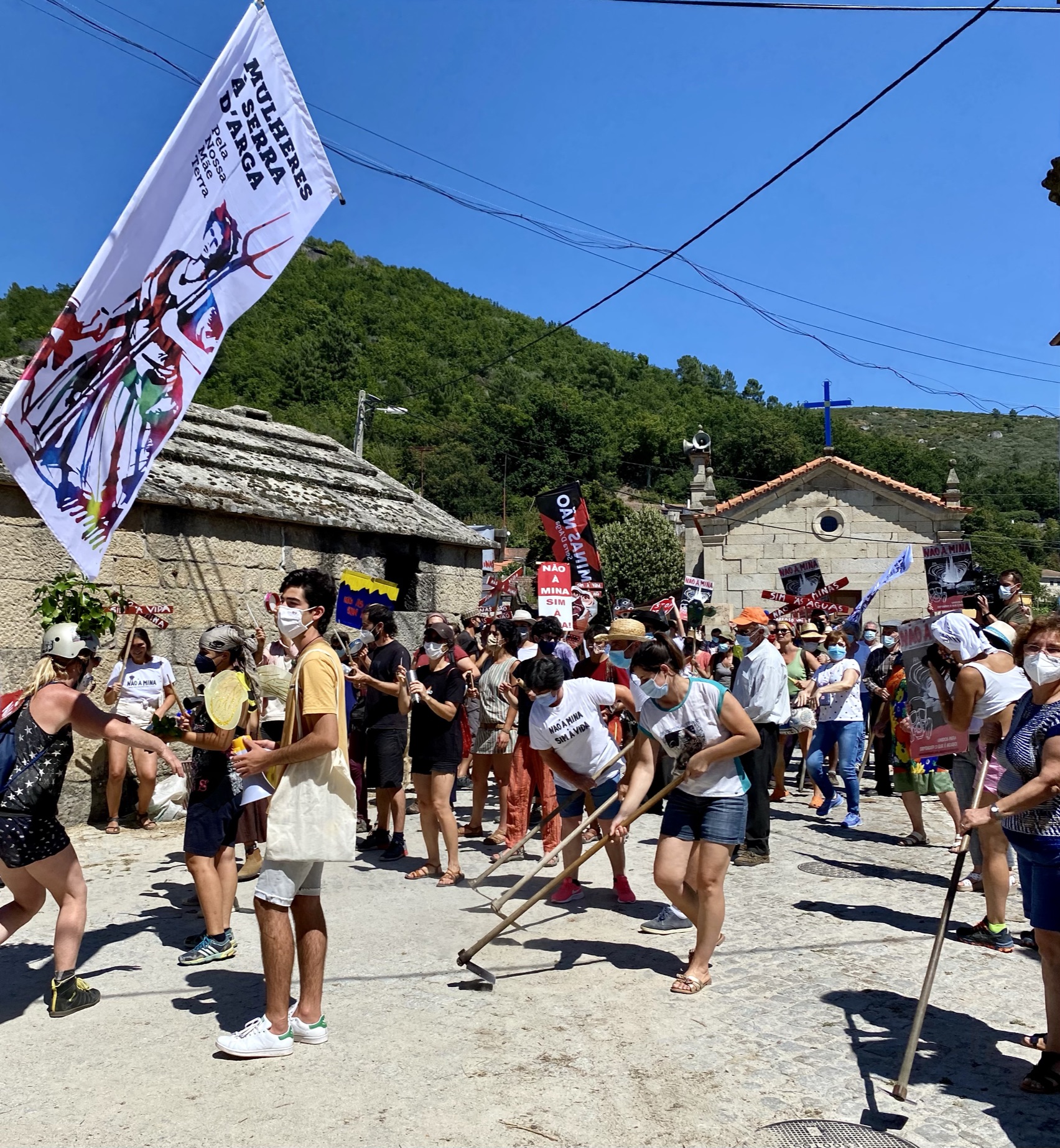 People gathered on the street of a village holding a banner.