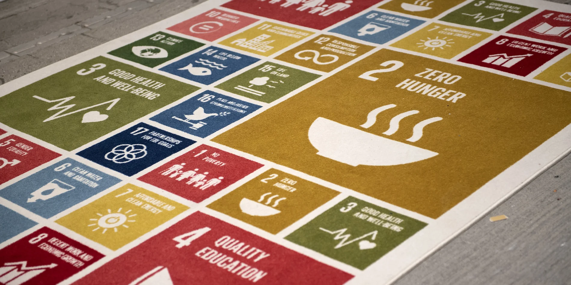 Mat with colorful squares on paved surface, outlining the UN SDGs.