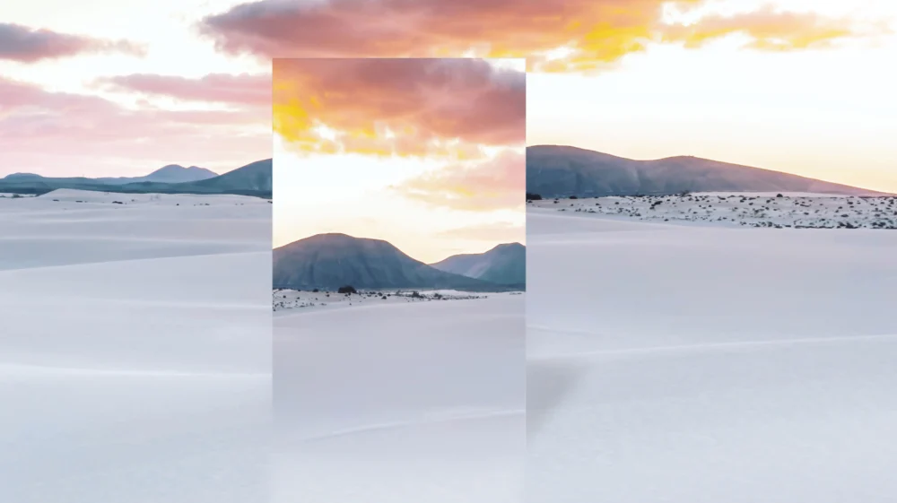 Mirror reflecting desert dunes with dramatic sunset sky.