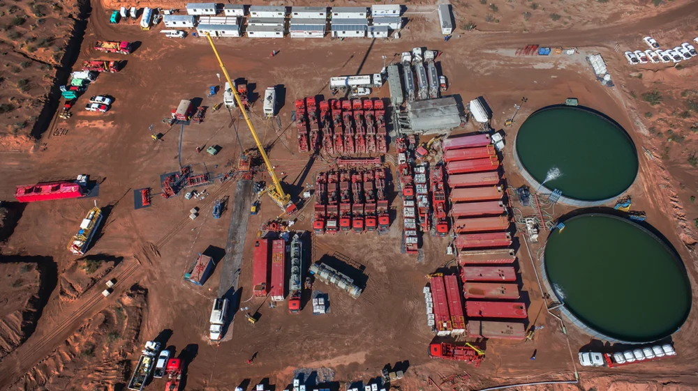 A battery of pumping trucks is lined up behind pools of water to be used for hydraulic fracturing in Vaca Muerta, Argentina.