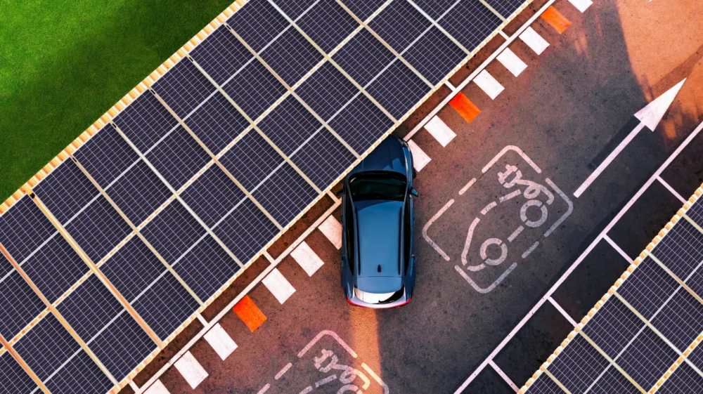Aerial view of electric car parking in charging station with solar panels