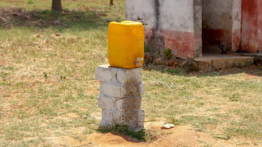 A yellow plastic at a rural latrine mounted on a stack of bricks.