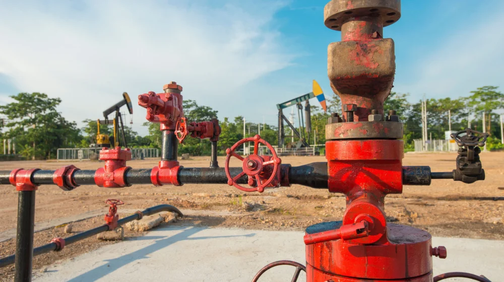 Red and grey pumps, with oil well heads painted with the Colombian flag colours in the background.