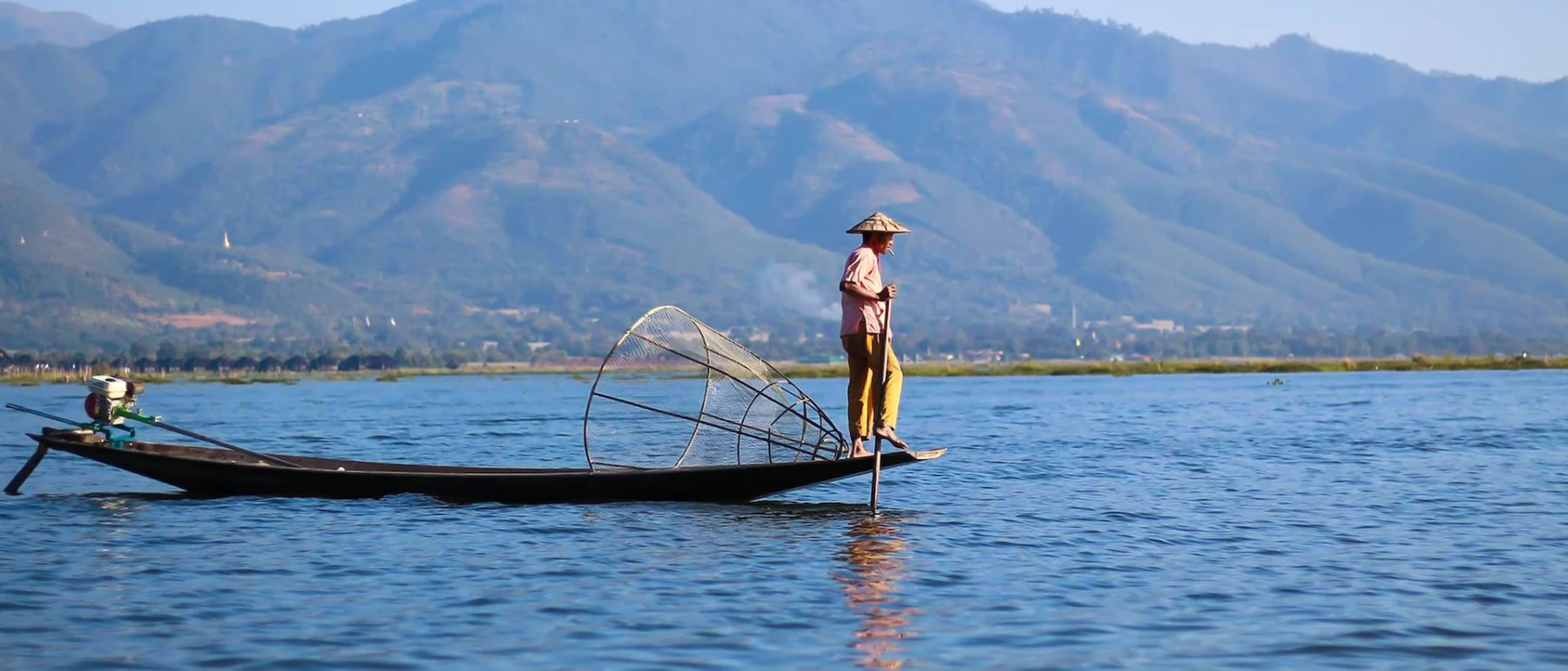 woman-in-white-shirt-and-brown-hat-standing-on-boat-on-body-of-water-during-daytime