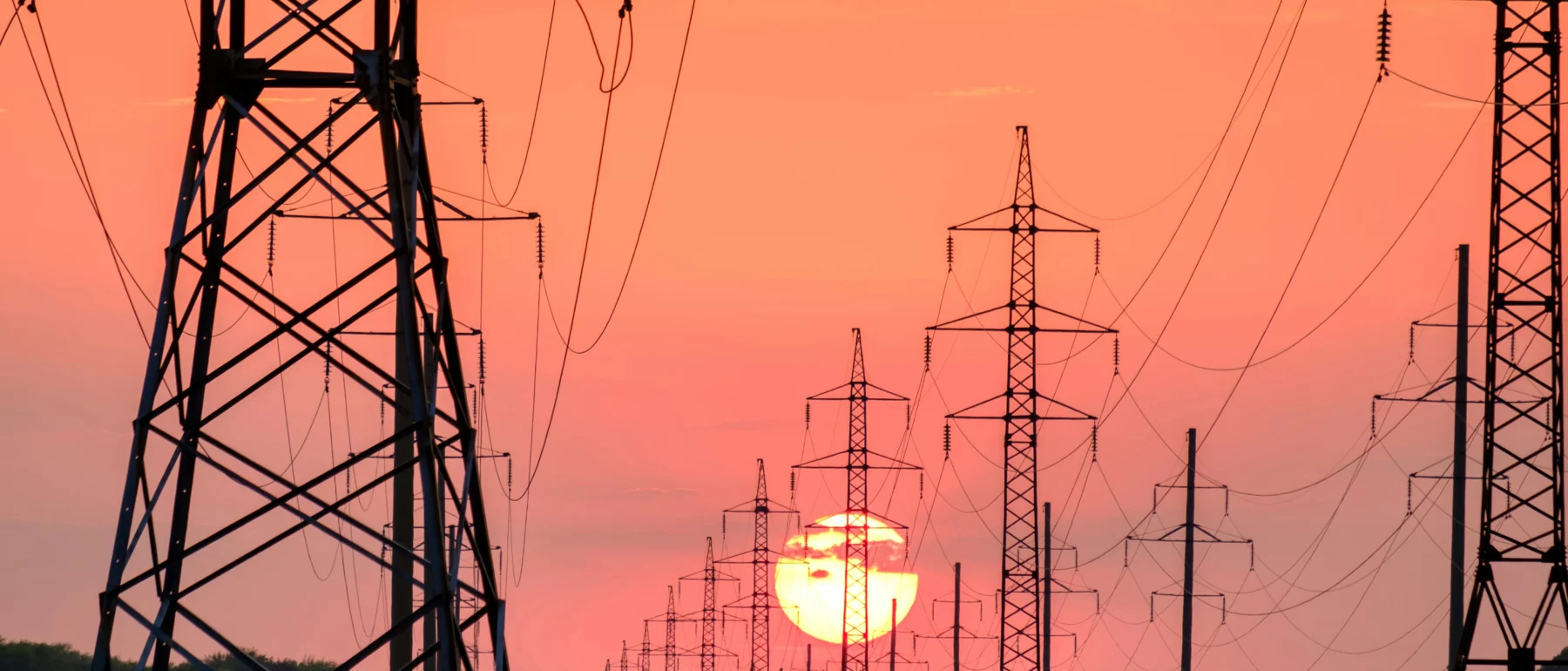 Sunset in the background, electric power grid in the foreground.