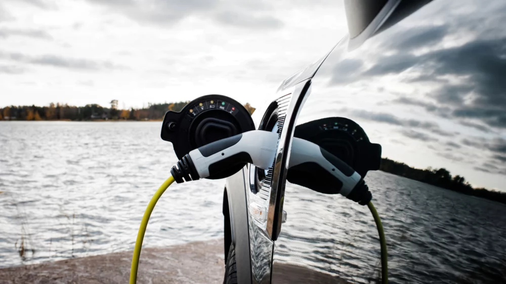 Close-up shot of an electric car plugged into a charger next to a beach in Norrtälje, Sweden.
