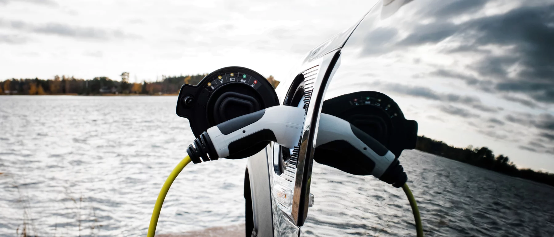 Close-up shot of an electric car plugged into a charger next to a beach in Norrtälje, Sweden.
