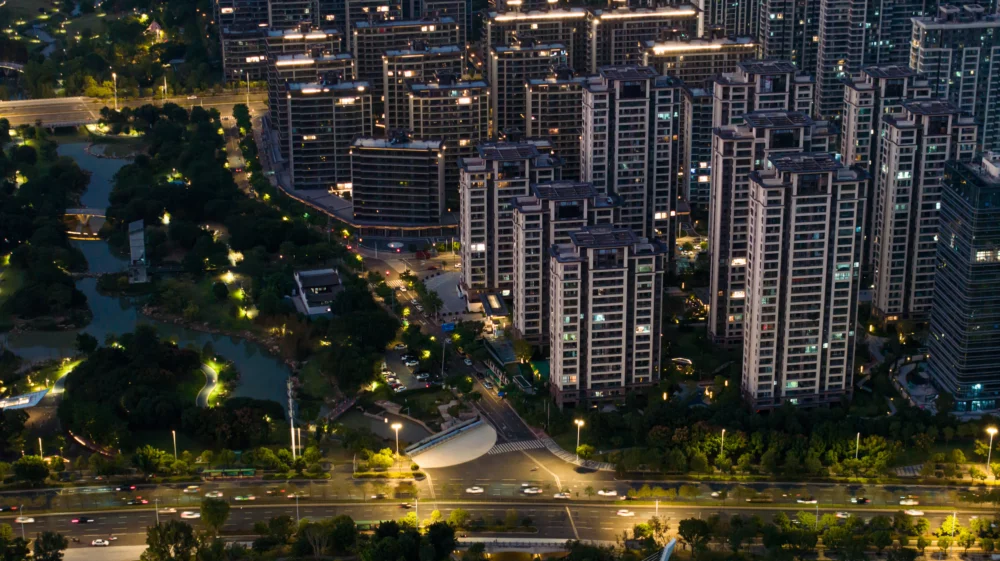 Night view of high-rise building next to a urban green space with bright street lamps