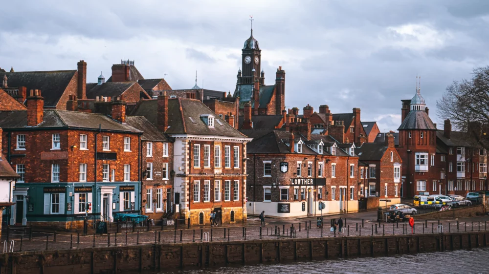 Brick buildings on the along a bollarded road on the edge of the river Ouse in York.