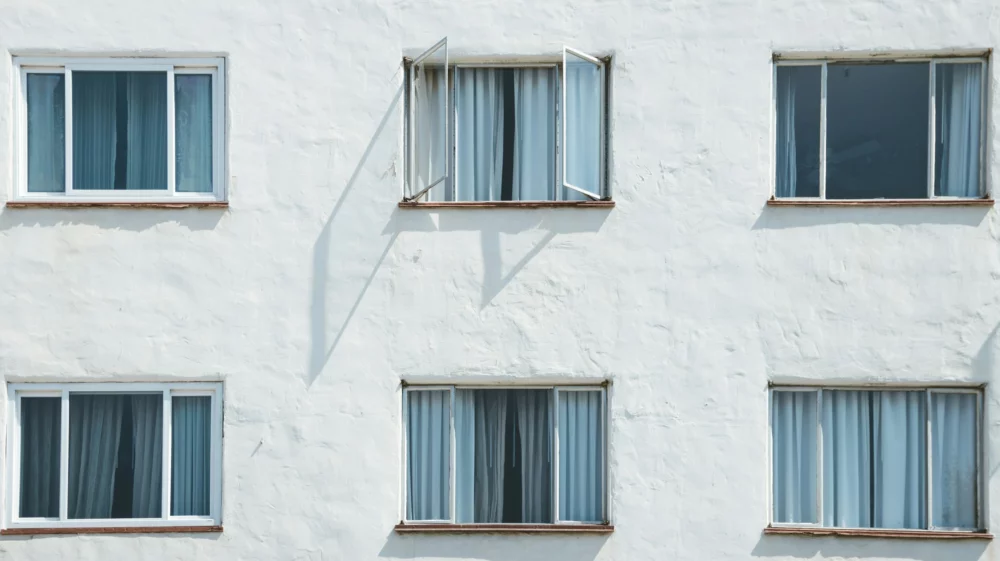 Six windows on a white wall in a grid; three across, two down. The middle window on the top row is open.