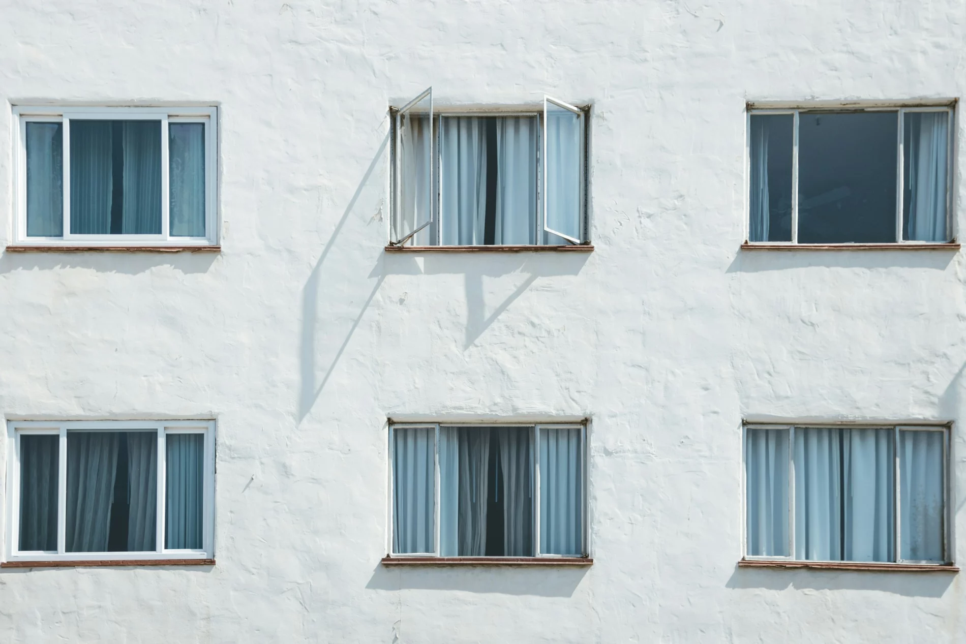 Six windows on a white wall in a grid; three across, two down. The middle window on the top row is open.