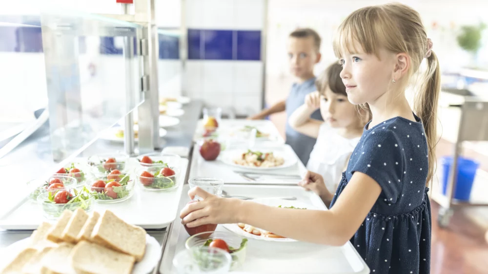 Girl taking apple at lunch in school cafeteria