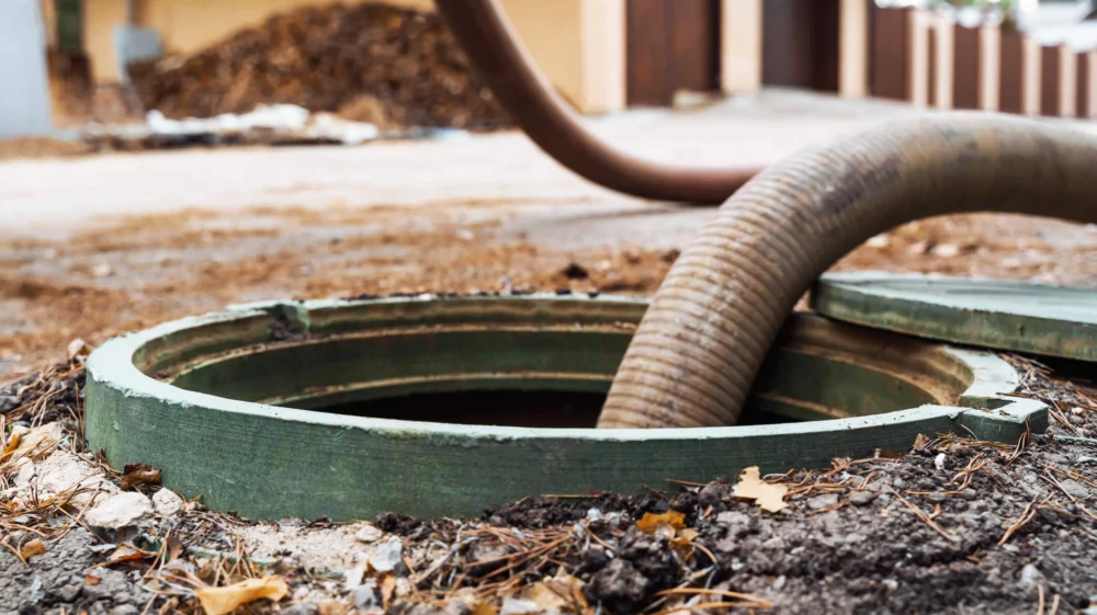 Close-up of an open septic tank with a hose inserted for waste removal.