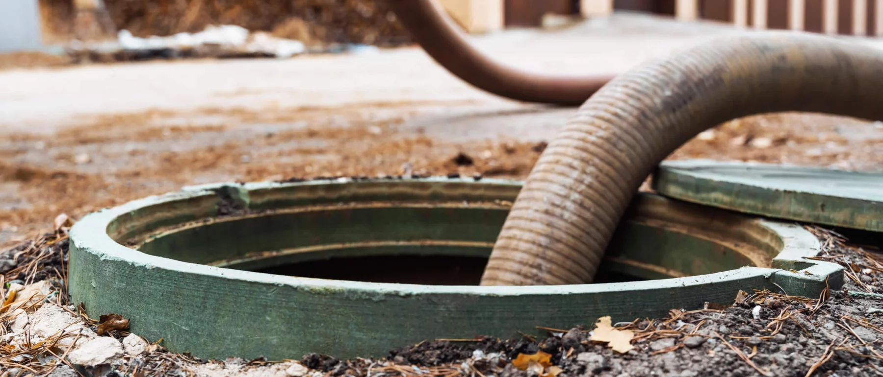 Close-up of an open septic tank with a hose inserted for waste removal.