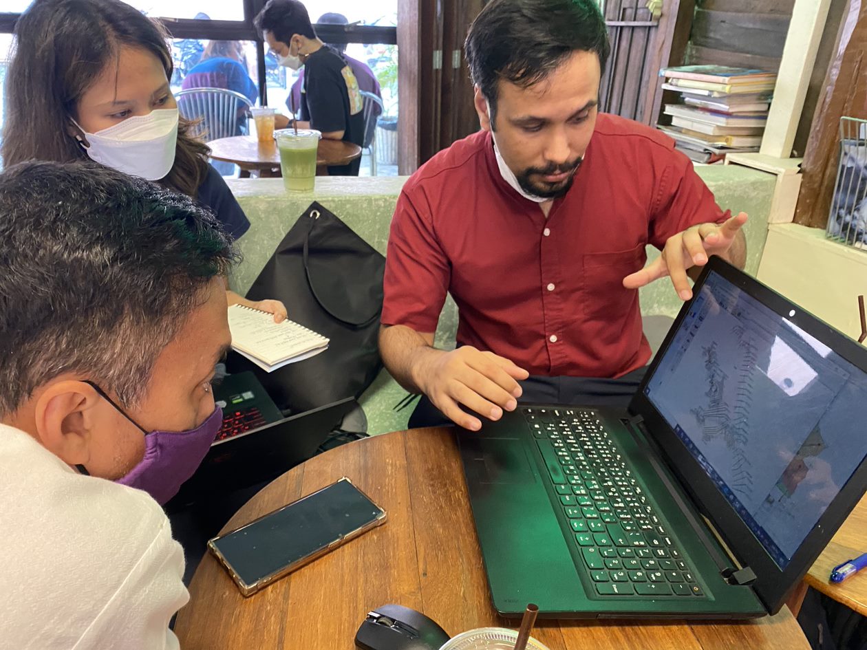 The Mayor of Mae Sai district, Chaiyon Srisamut, discusses flood modelling with SEI researchers Uttam Ghimire and Parichat Pinsri. They are seated around a table with a laptop displaying a map.