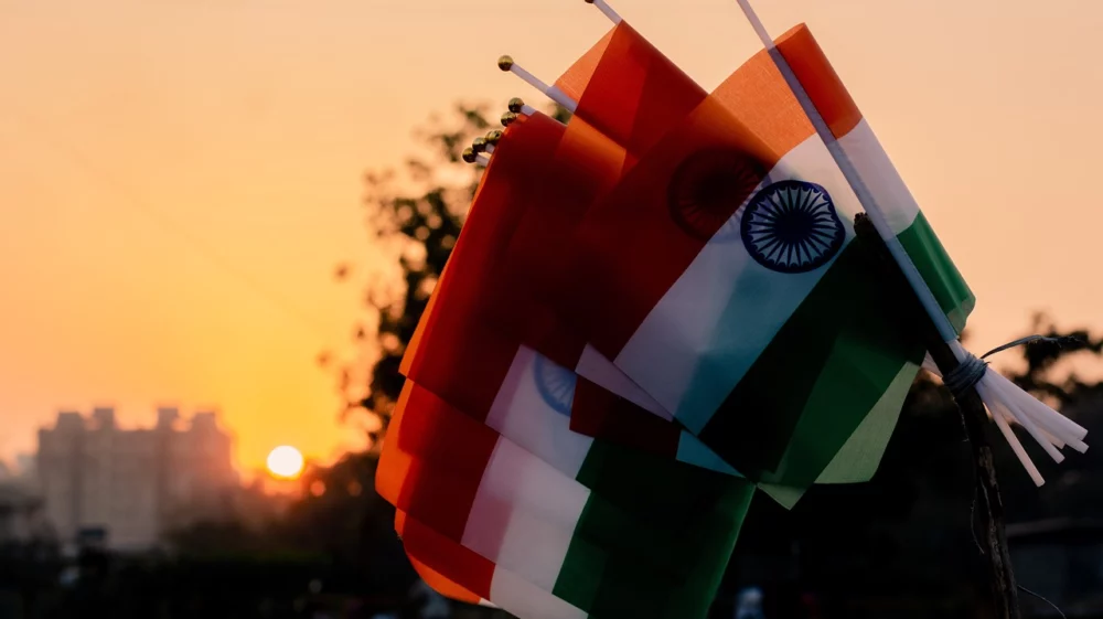 A series of Indian flags dipped with the sun setting behind them.